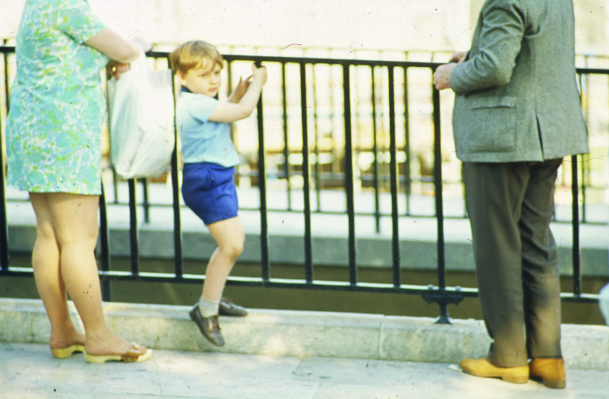 Bored child climbing rails with parents.